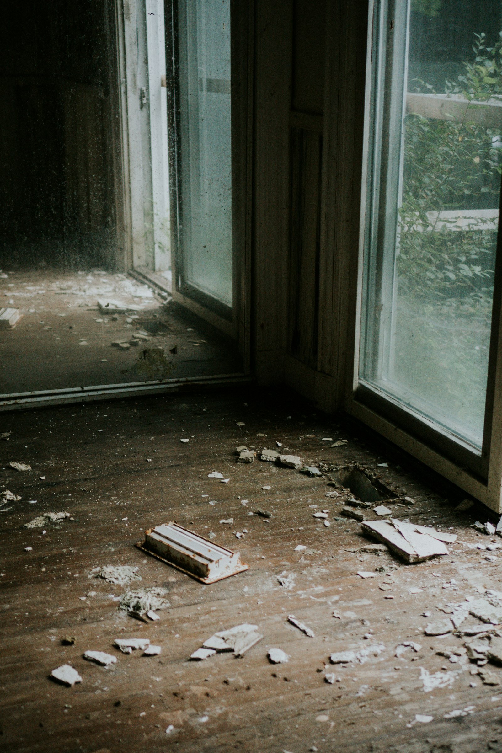 Debris and water damage on the floor of a home near a window